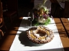 Roscón de Reyes hecho con una masa de hojaldre relleno de crema pastelera, chocolate negro. Untado con huevo y espolvoreado con azúcar moreno. Decorado con almendras laminadas, uvas peladas sin pepitas, nueces y espolverado con azucar glacé.